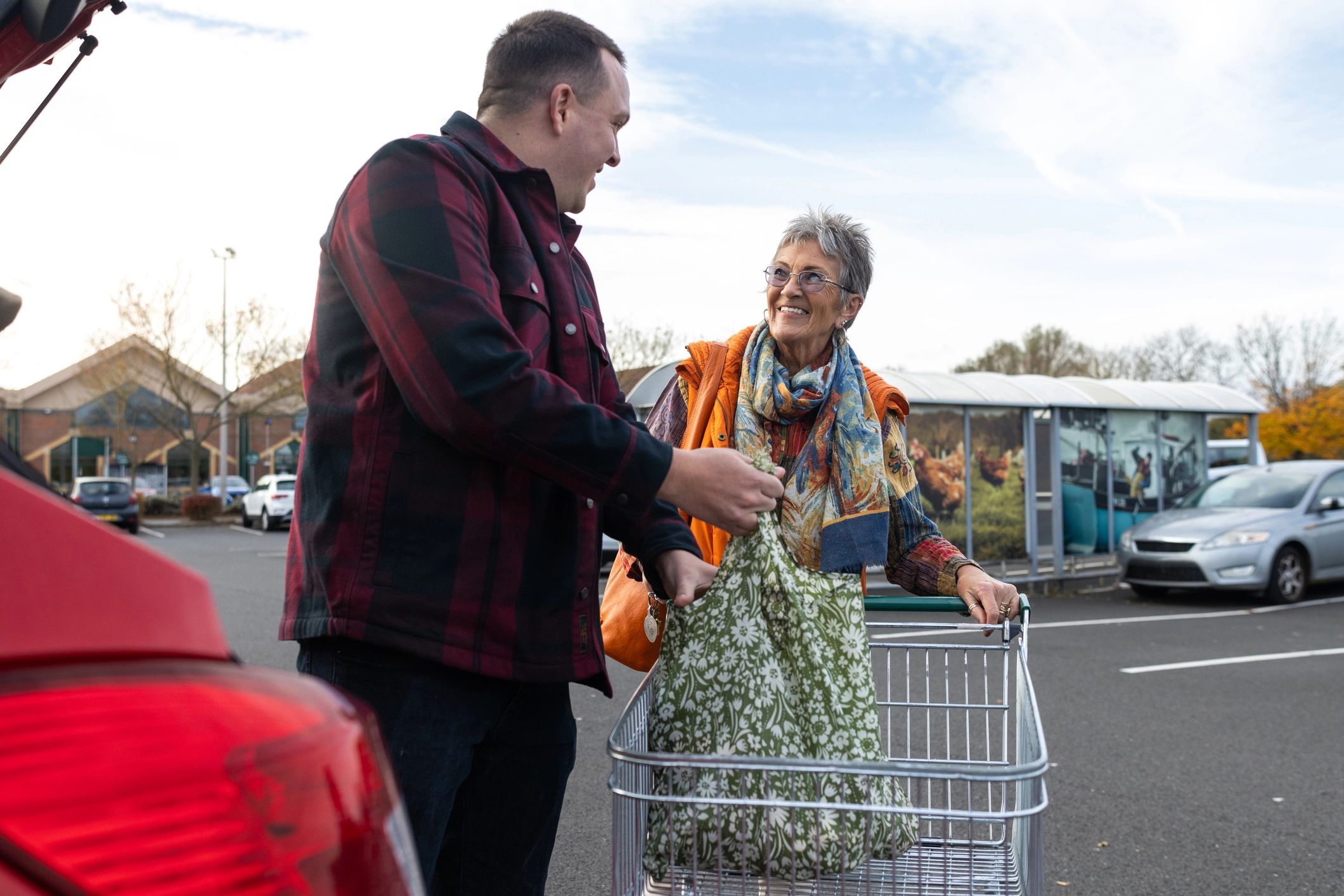 Family member helping an older adult load groceries into a car